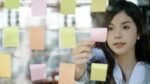 A woman placing a sticky note onto a transparent surface